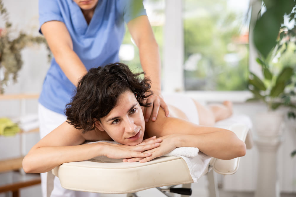 Masseur doing back massage to adult woman