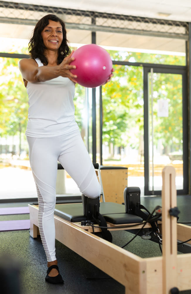 Portrait of positive hispanic woman practicing with pilates bender ball