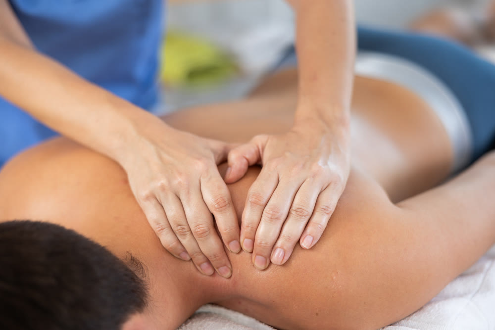 Man receiving massage relax treatment close up. Masseur hands doing back massage in spa center
