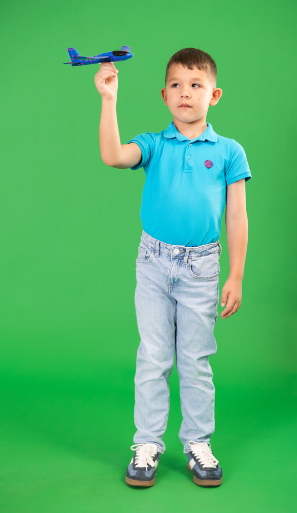 Child boy in jeans holds toy foam airplane in hands