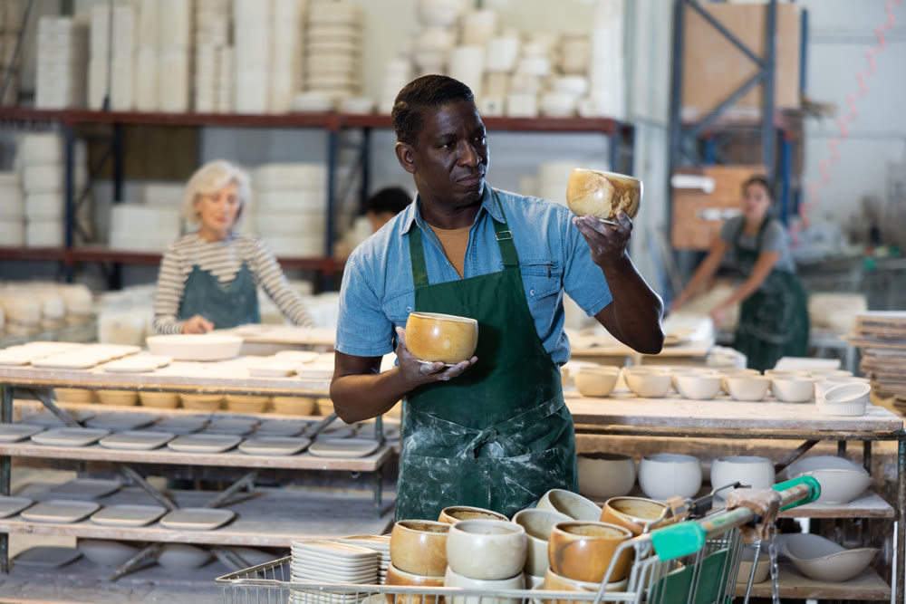 African american man checks quality of pottery after being removed from plaster mold