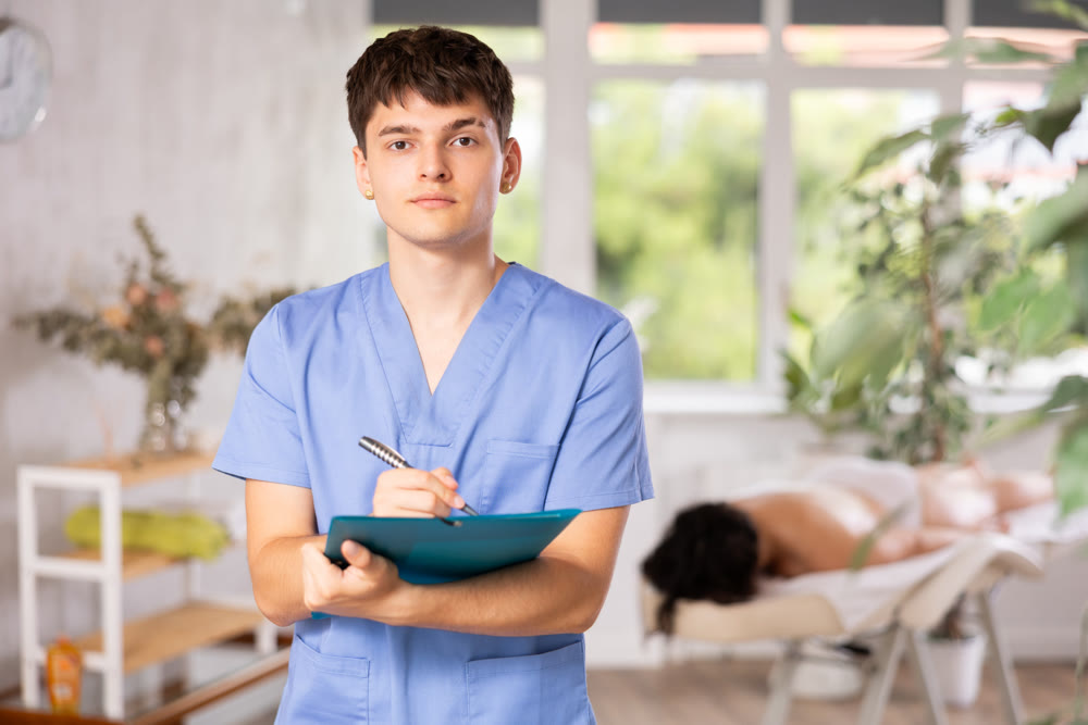 Young guy masseur makes notes in office