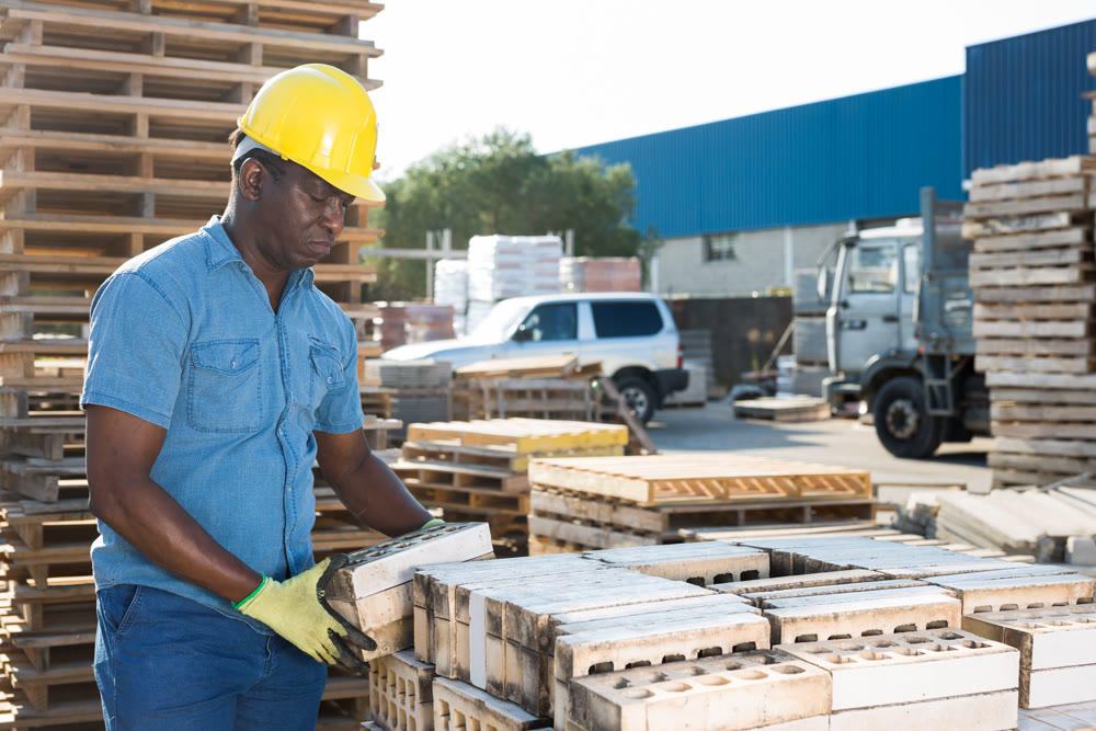 man is checking quality of bricks in the open area of a construction store