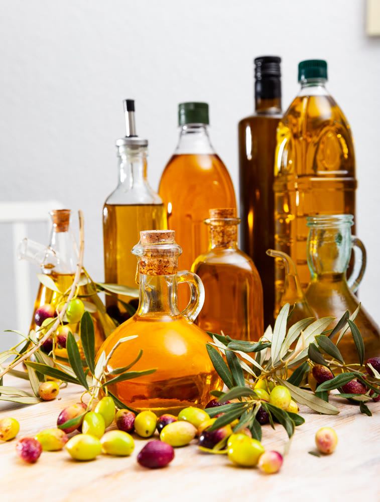 Bottled olive oil and branches with leaves and olives