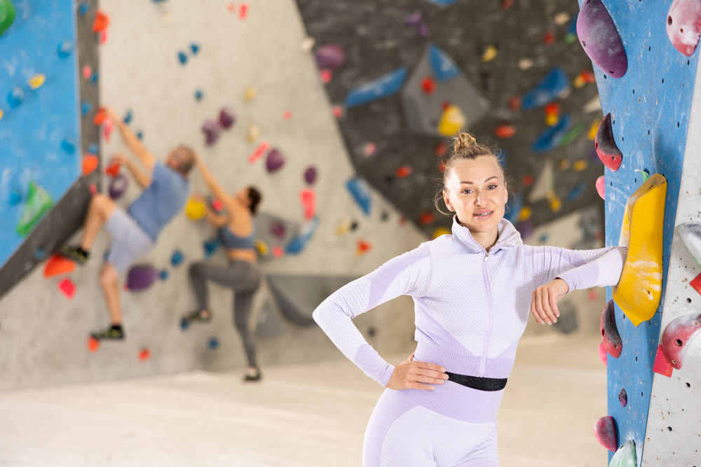 Satisfied confident woman standing near bouldering wall in climbing gym