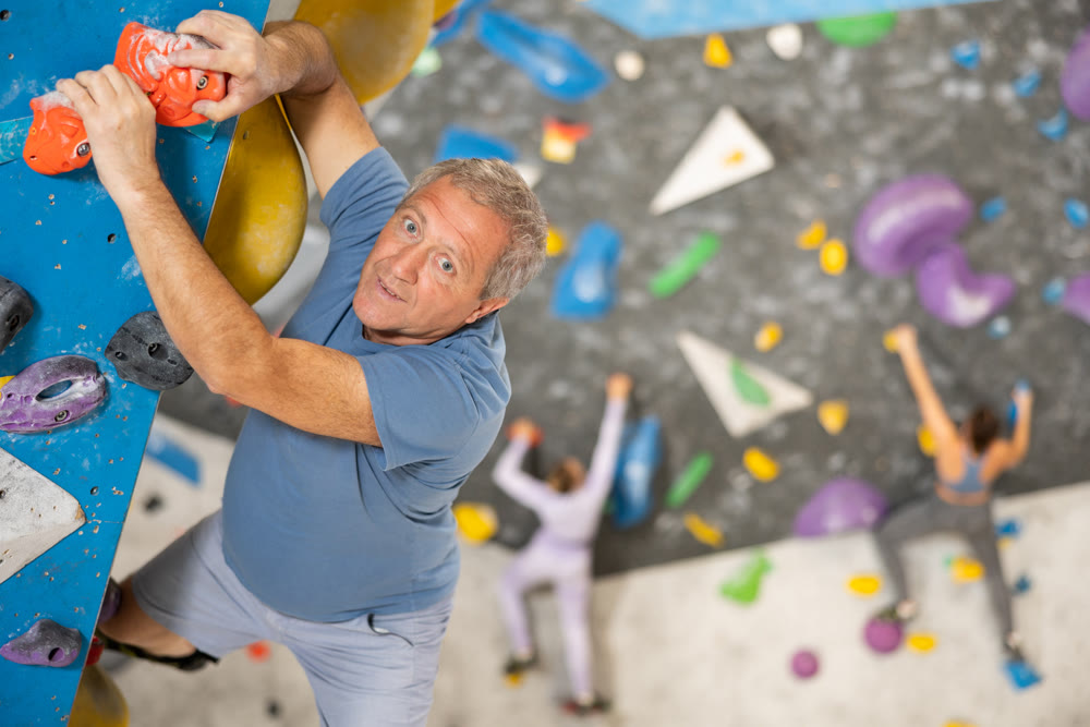 Adult man practicing rock climbing on climbing wall