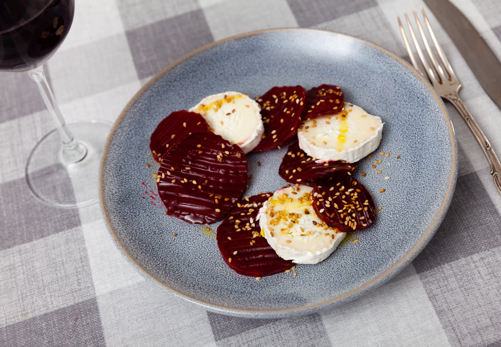 Delicious salad of baked beetroot with creamy goat cheese and decorated sesame seeds serving on plate