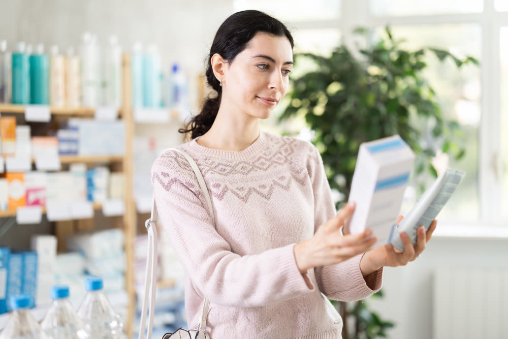 Young woman choosing a cream in a pharmacy