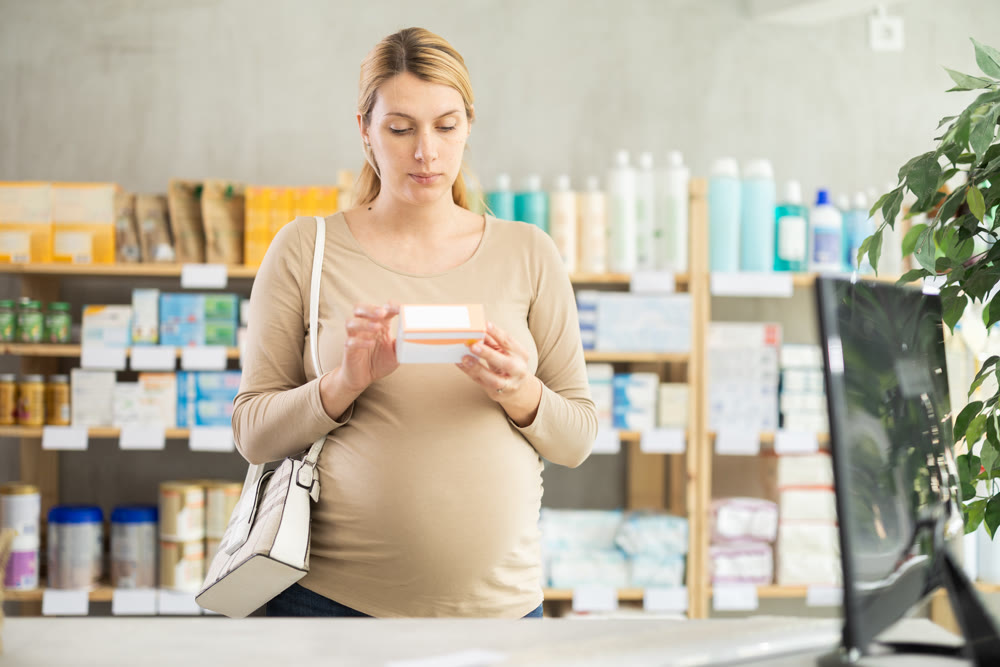 Pregnant woman customer choosing pills in box in drugstore