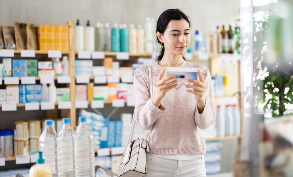 Young woman chooses ointment at pharmacy