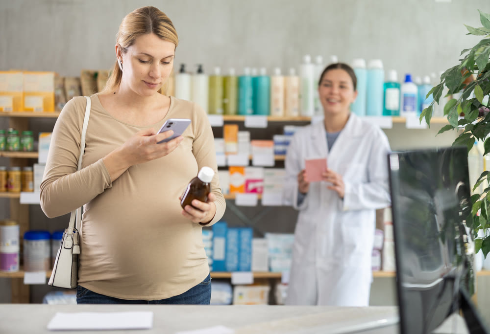 Pregnant woman buyer scans syrup qr code with woman pharmacist