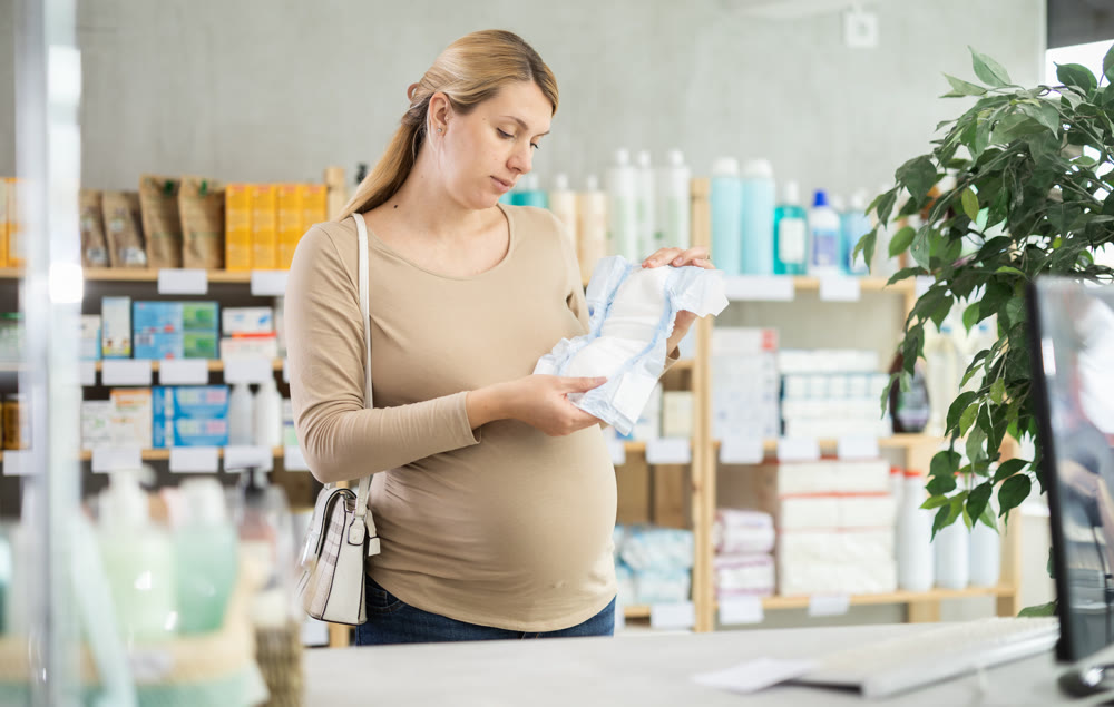 Pregnant woman customer choosing diapers in drugstore