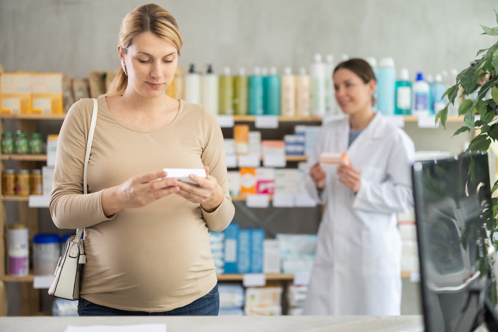 Pregnant woman choosing pills with help of pharmacist