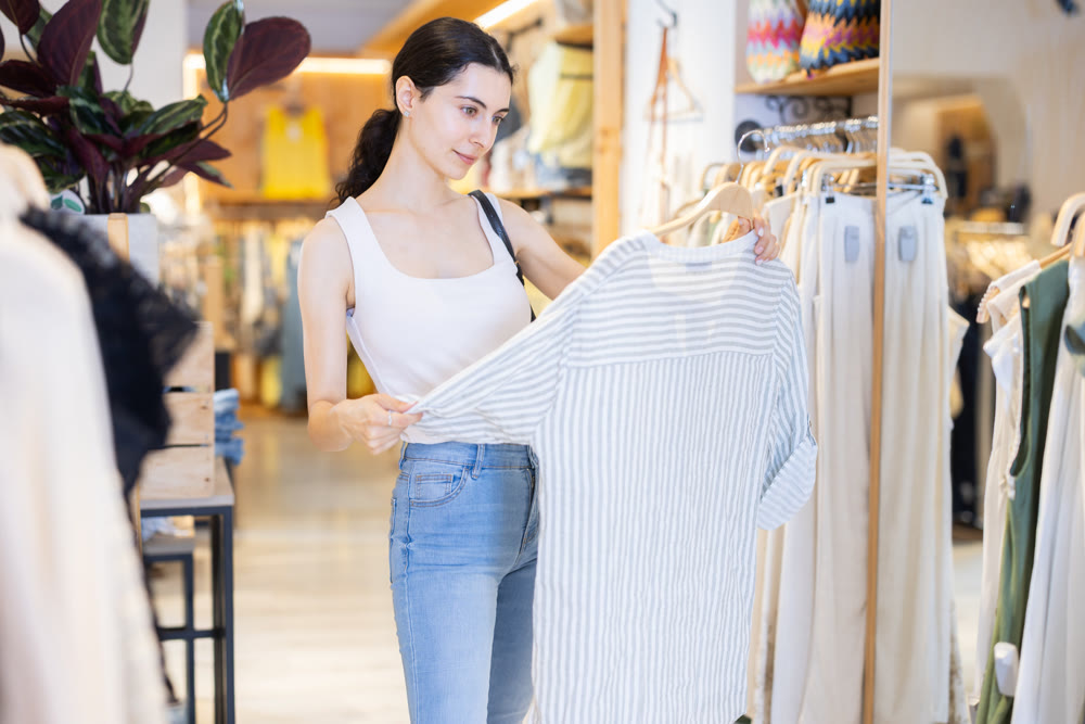 Girl customer chooses blouse in branded store