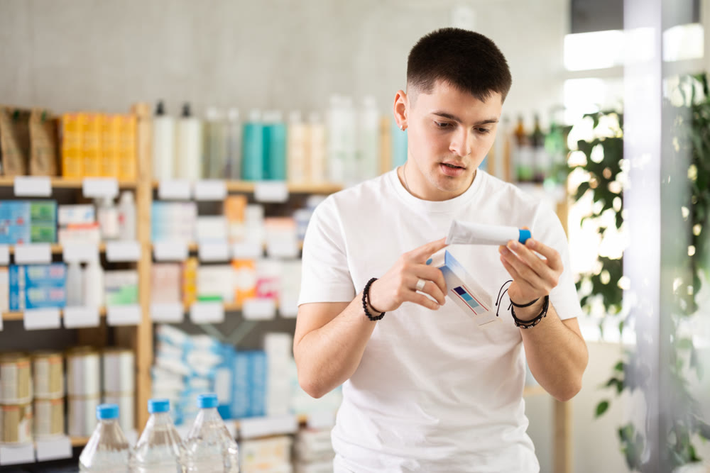 guy chooses an ointment in a European pharmacy