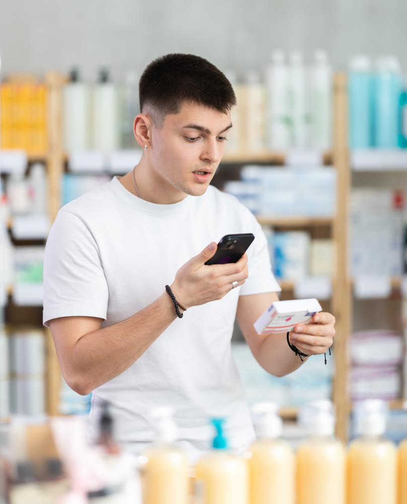 Young man in pharmacy scans QR code on paracetamol box