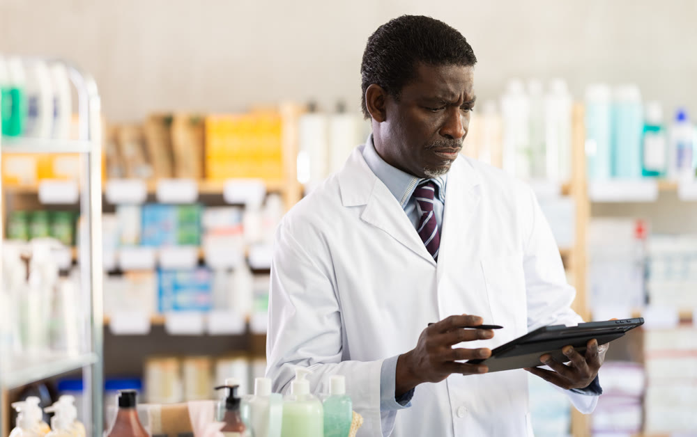 Pharmacist managing prescriptions with tablet in pharmacy