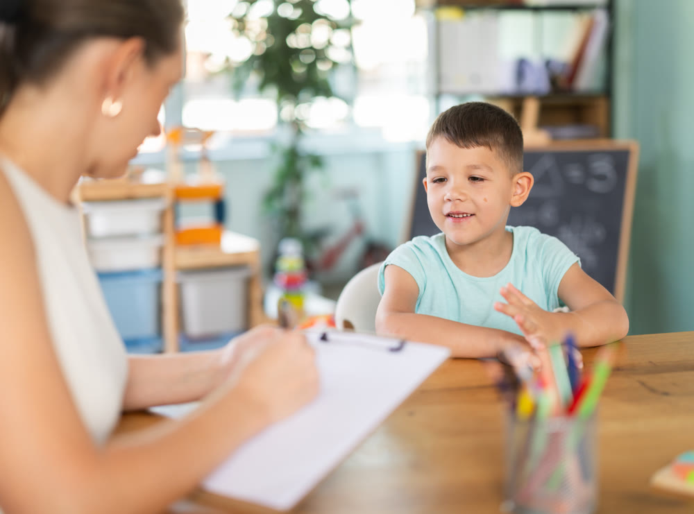 Child psychologist fills out questionnaire and interviews boy in kindergarten.