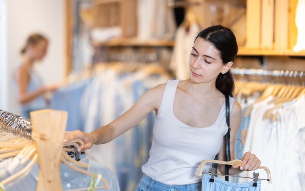 Young woman choosing skirt in clothing store