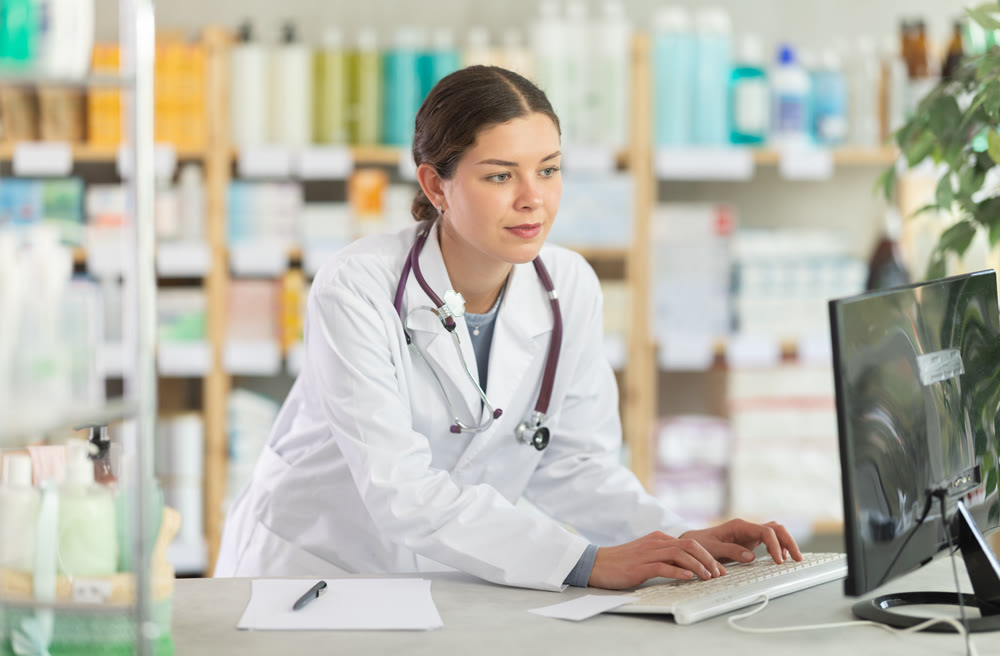 Pharmacy employee entering medical data into computer system