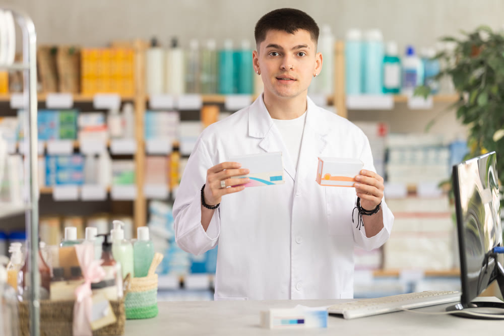 Young man pharmacist uses computer at workplace