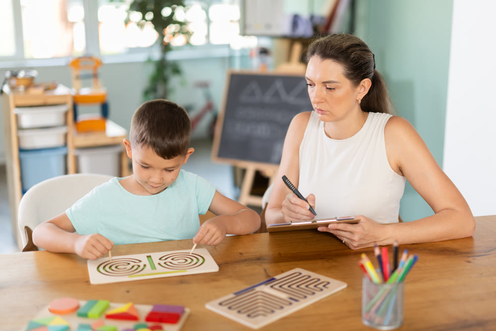 Child psychologist observing boy tracing labyrinths with both hands