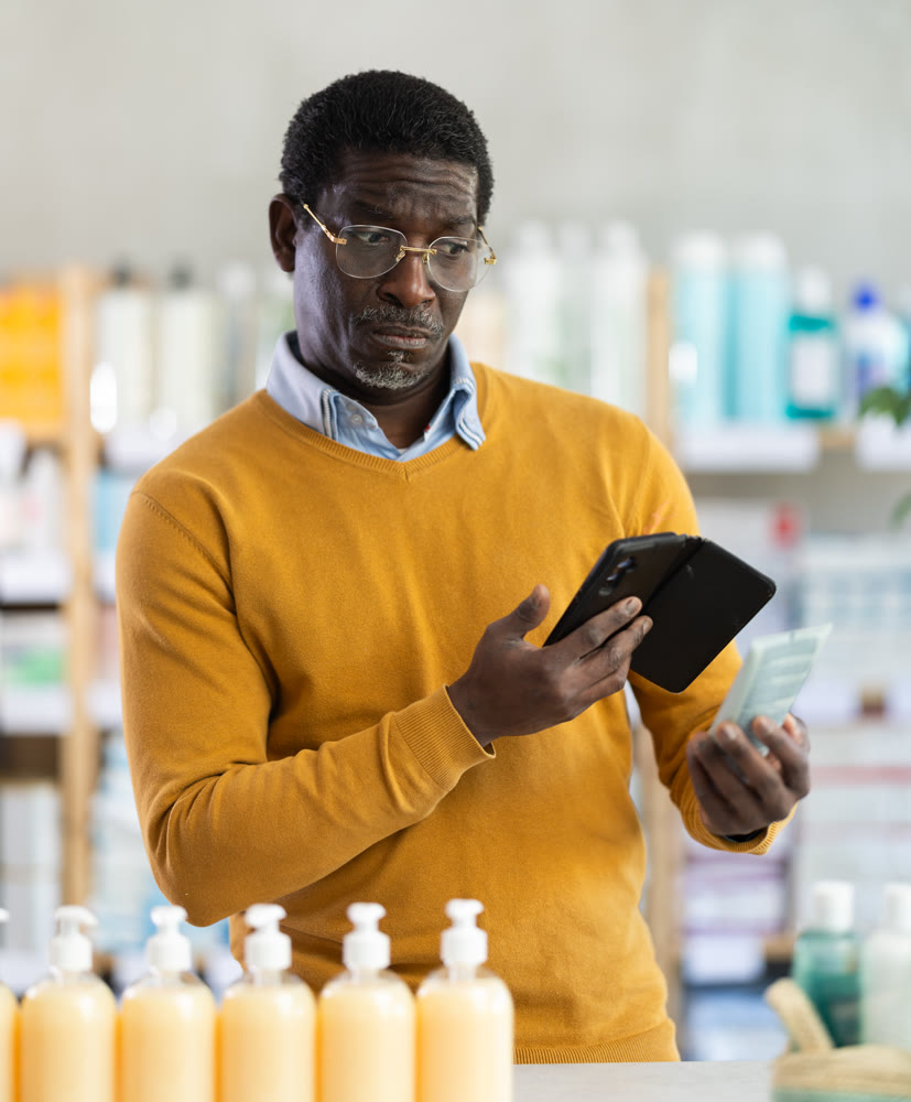 African man in pharmacy scans QR code on cream