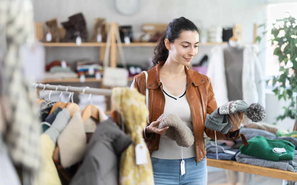 Young woman choosing hat in clothing store