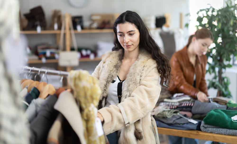 Armenian girl near showcase examine goods, buying something autumn outwear.