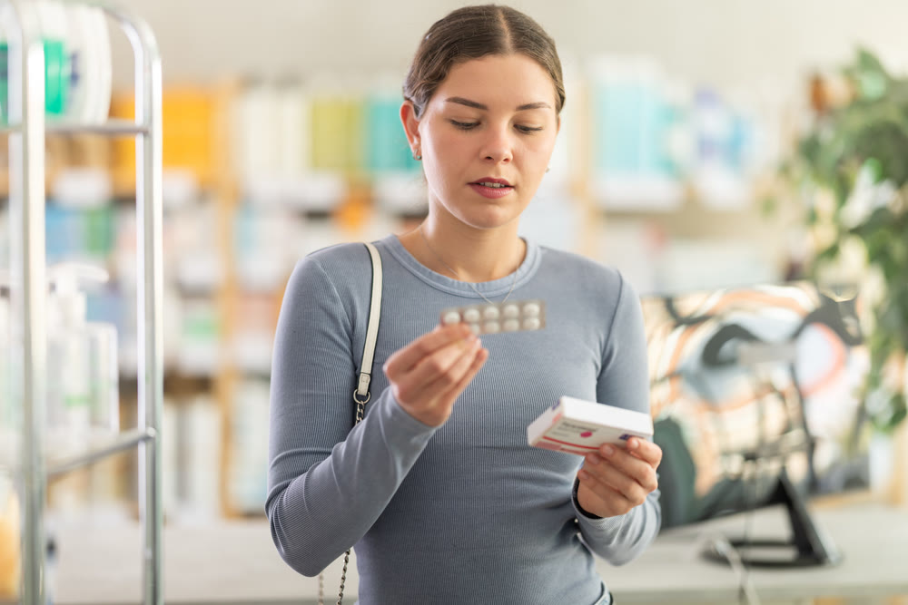Woman checking blister pack and box of paracetamol in drugstore