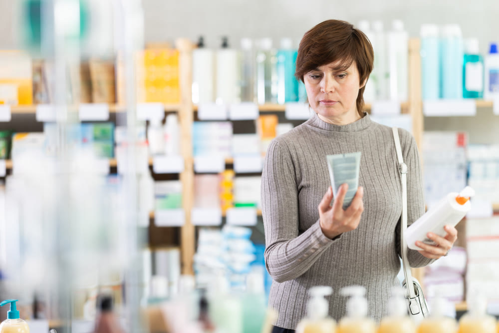 Woman in autumn clothes choosing skin cream at drugstore