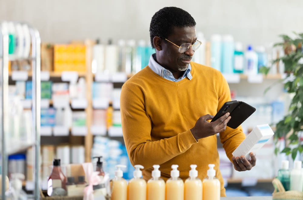 African man in pharmacy scans QR code on cream