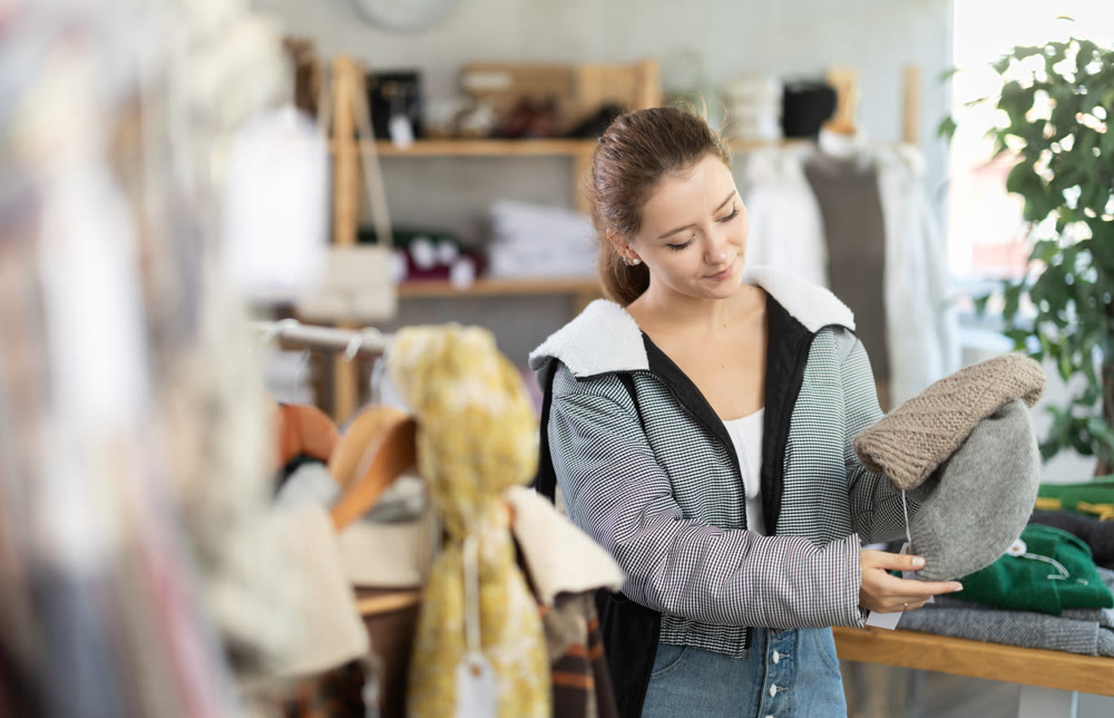 Young woman choosing hat in clothing store