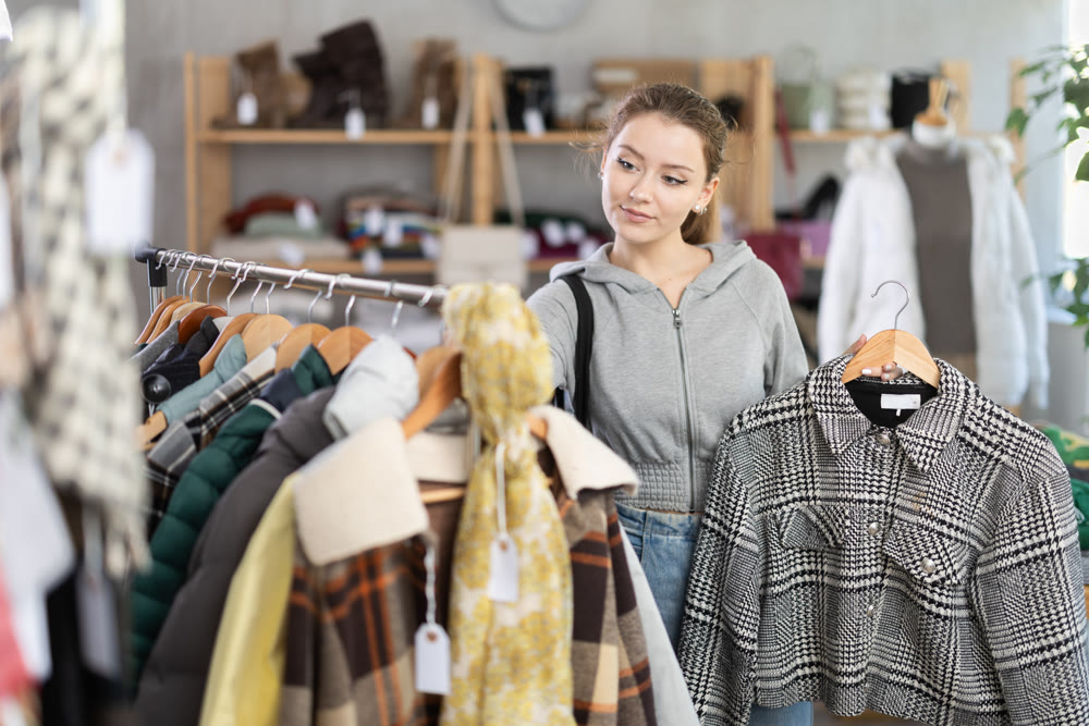 Young woman chooses jacket in clothing store