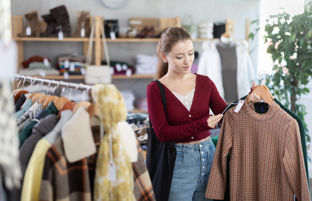 Young woman chooses warm dress in clothing store
