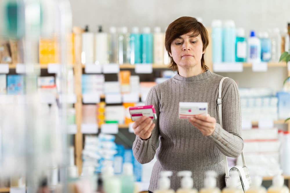 Woman examining packs of paracetamol tablets at pharmacy
