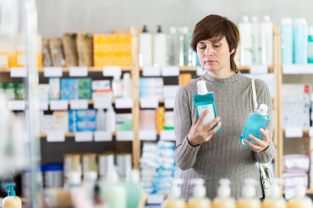 Interested female customer choosing mouthwash at pharmacy