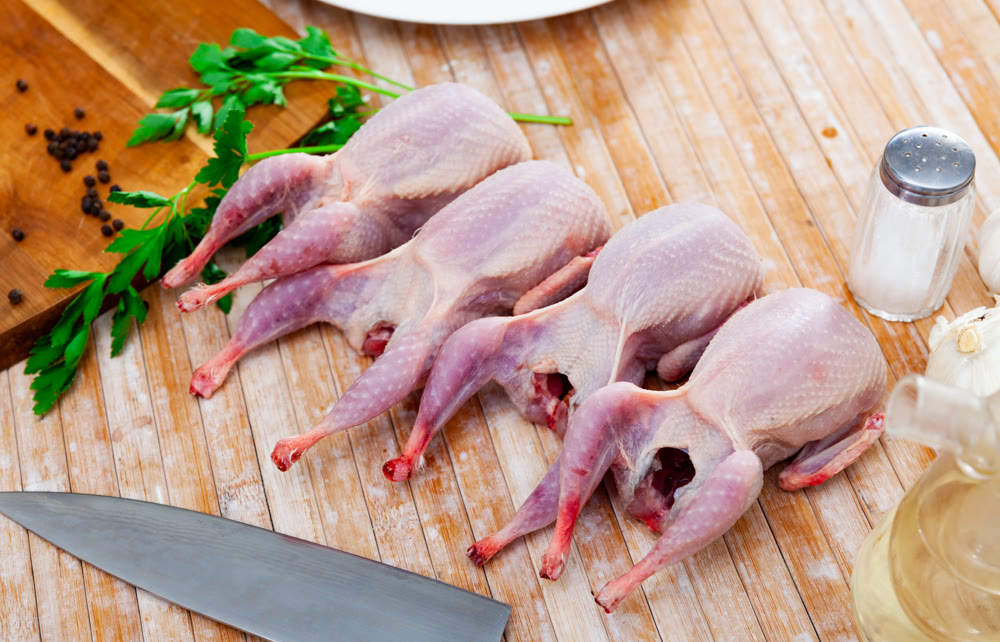Uncooked quails on wooden table