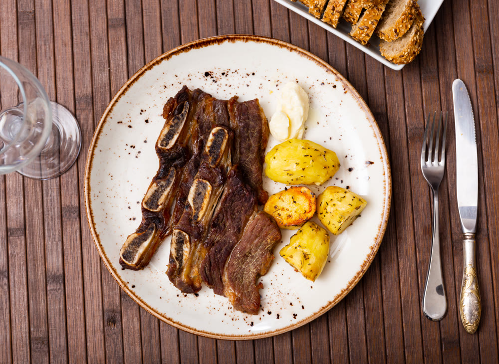 Grilled beef spare ribs with baked potatoes and sauce