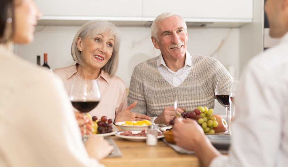 Elderly parents enjoying family dinner with adult son and daughter-in-law