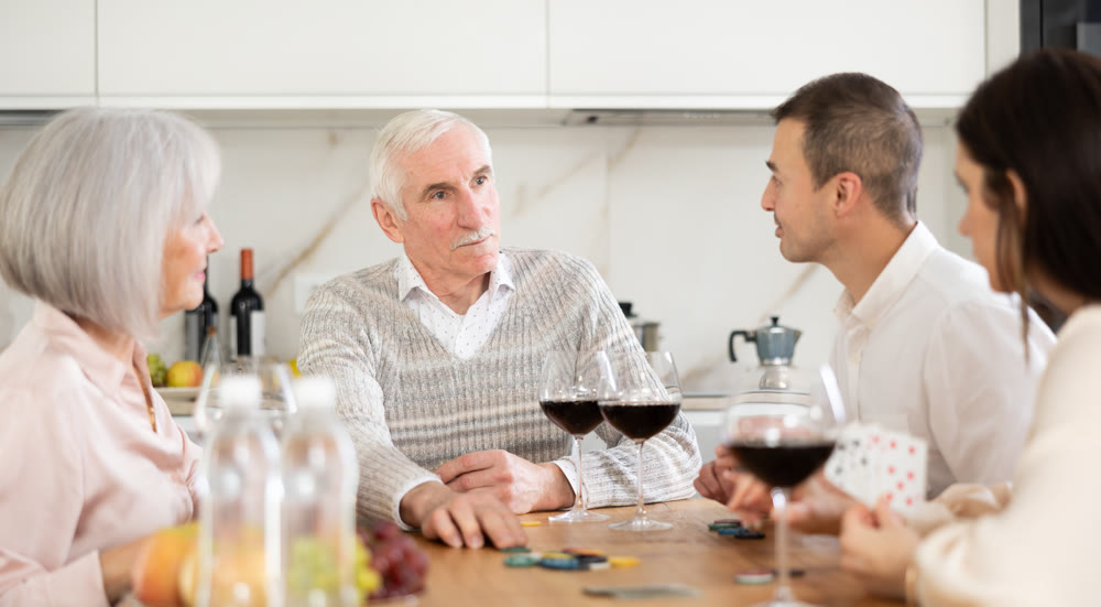 Mature married couples playing card game poker with younger spouses