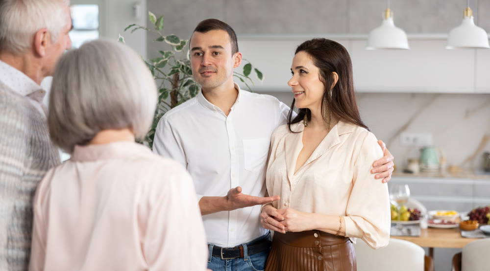 Smiling man introducing girlfriend to elderly parents at home