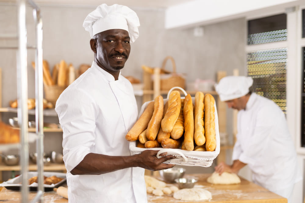 Adult man baker with basket of baguettes