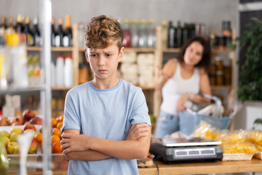 Sad boy while shopping with mother at grocery store