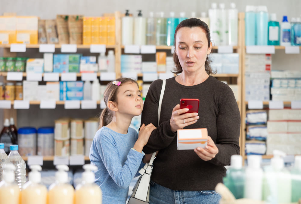 Woman with daughter in pharmacy scans QR code on tablet box