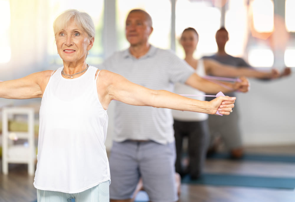 Mature woman bring together and spread your straightened arms at chest level with resistance band