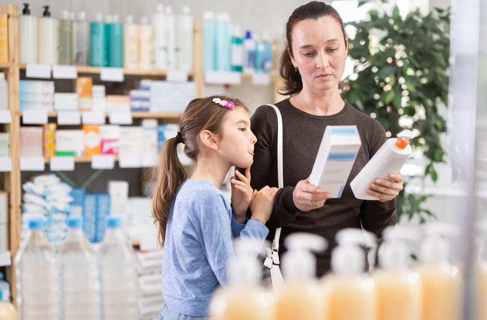Woman with daughter choosing cream in pharmacy
