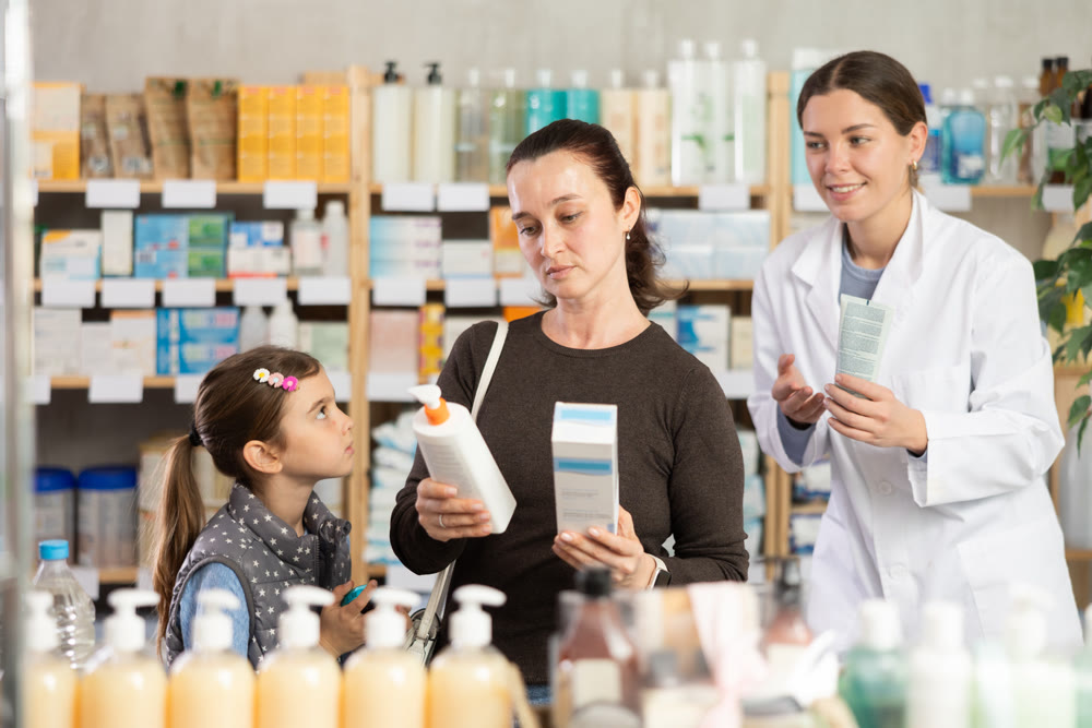Mother with tween daughter choosing sunscreen with pharmacist help