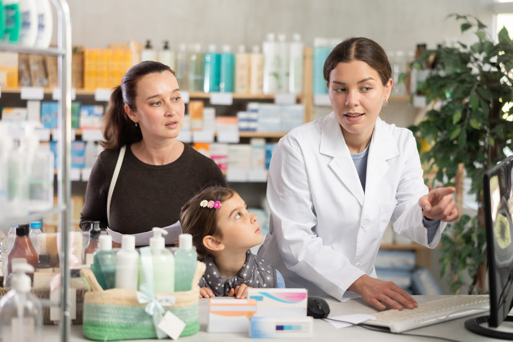 Girl pharmacist near computer during family consulting
