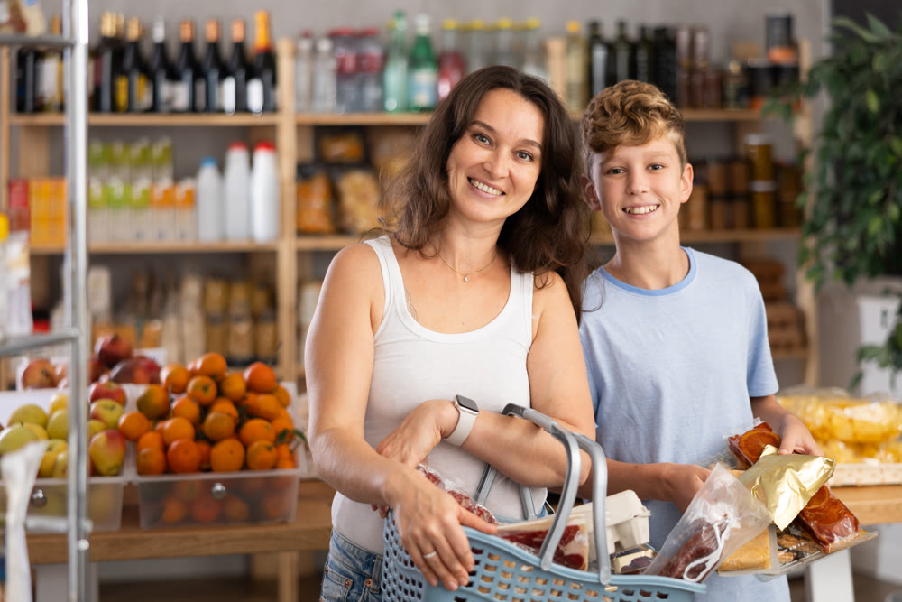 Adult woman with son choosing groceries in store